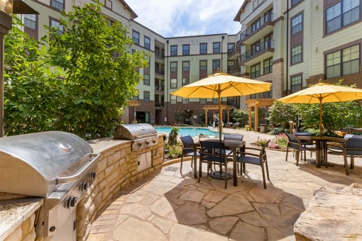 Grilling area with gas grills and patio seating with umbrellas at 1010 Dilworth Apartments, Charlotte North Carolina