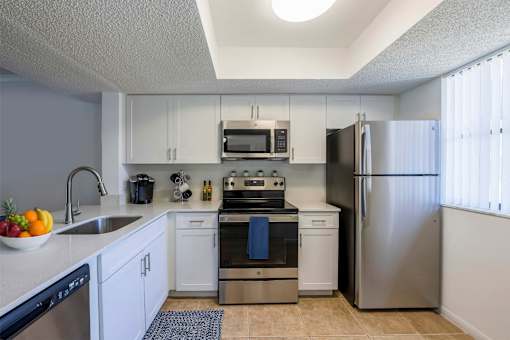 A kitchen with white cabinets and stainless steel appliances at Waterview at Coconut Creek, Florida 33073