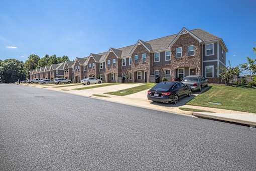 A row of houses with cars parked in front.