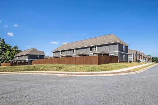 A row of houses with a grey roof and a brown fence.