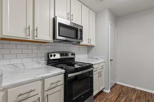 A kitchen with white cabinets and a black stove top oven.