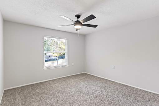 A room with a ceiling fan and a window.