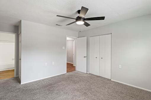 A room with a ceiling fan and carpeted floor.