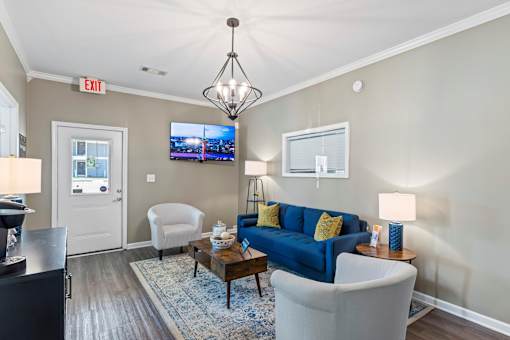 A living room with a blue couch and a television on the wall.