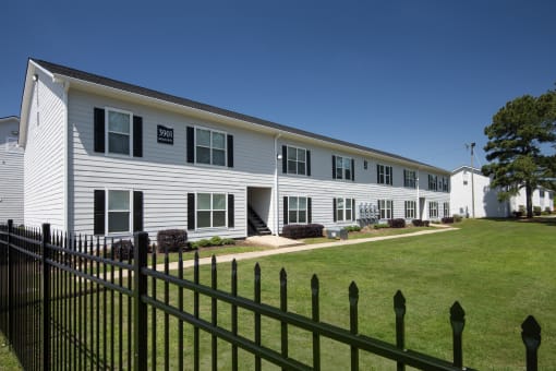 a white house with a green lawn and a black fence