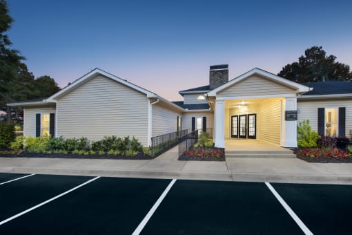 the exterior of a white building with a driveway and parking lot