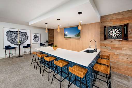 A modern bar area with a dart board on the wall.