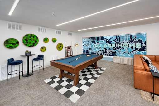 A pool table in a room with a blue couch and a wall with green circles.