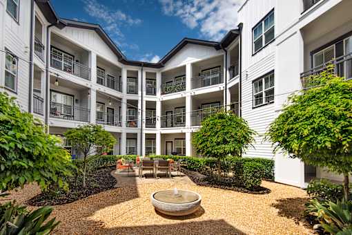 A courtyard with a fountain surrounded by white buildings.
