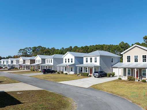 A row of houses with cars parked in front.