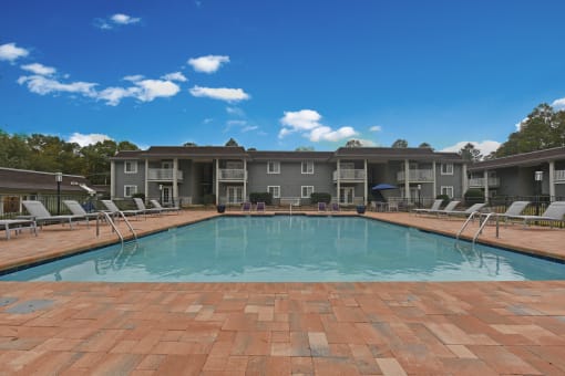 Apartments Near Region Field - MarQ Vestavia - Pool With Grey Sun Lounge Chairs, Brick-Style Flooring, Blue Sun Umbrella, And View Of Apartment Complex