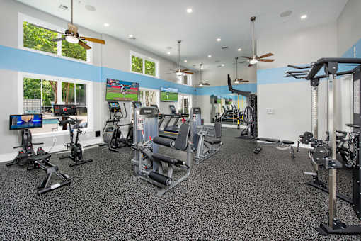 A spacious gym with a variety of equipment and a television screen.