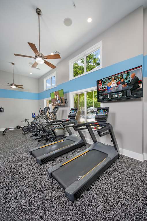 A room with treadmills and a television mounted on the wall.