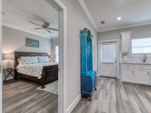 A bedroom with a bed, a blue cabinet, and a kitchen area in the background.
