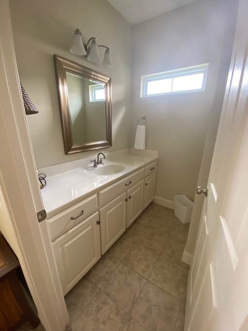 A bathroom with a sink, mirror, and a window.