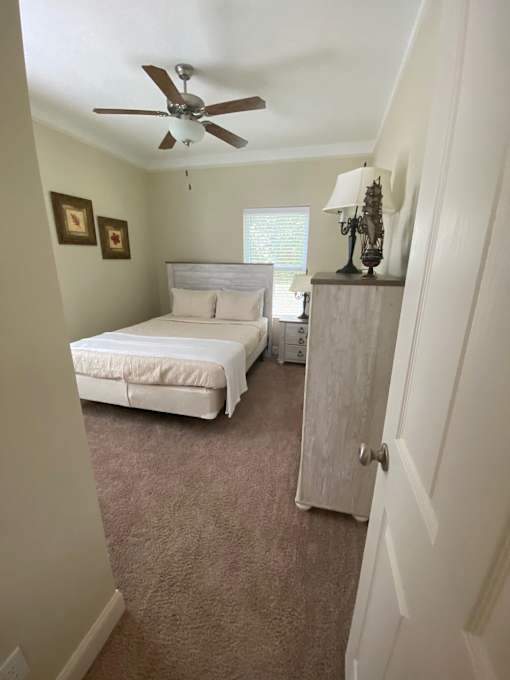 A bedroom with a bed, a dresser, and a ceiling fan.