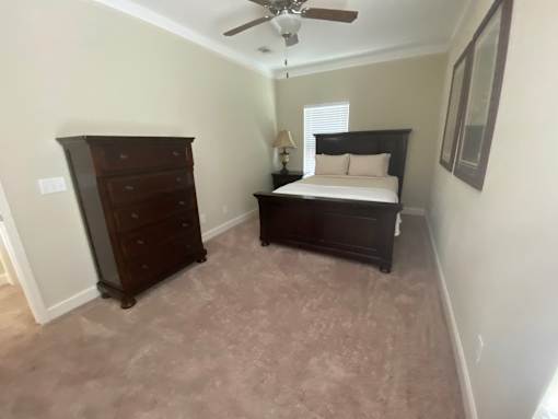 A bedroom with a bed, dresser, and ceiling fan.