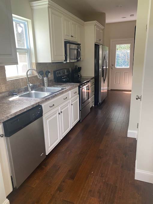 A kitchen with white cabinets and a black fridge.
