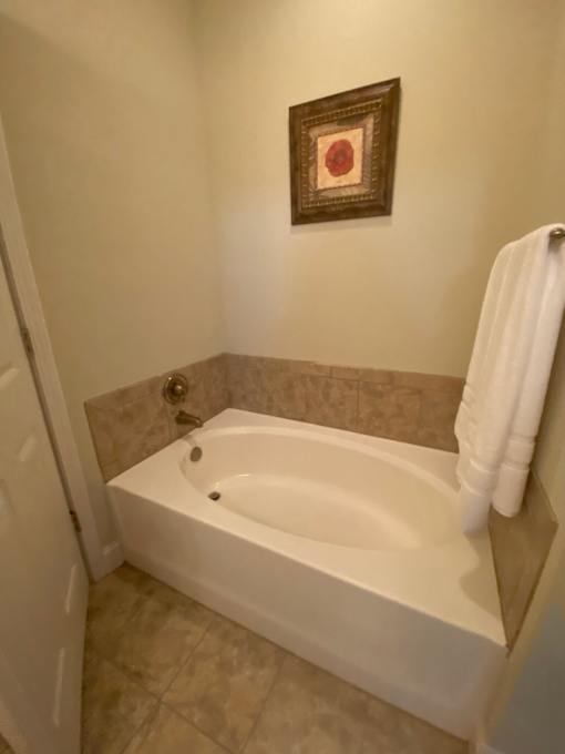 A white bathtub in a bathroom with a picture frame on the wall.