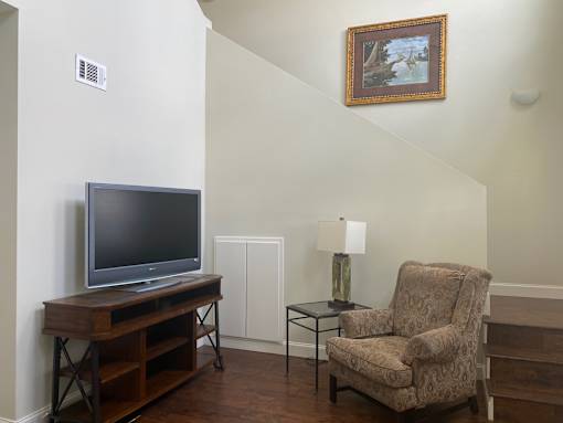 A living room with a chair, a table, and a television.