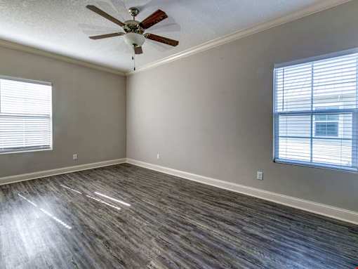 A room with a ceiling fan and wood flooring.