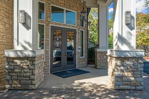 A building entrance with a stone pillar and a black mat.