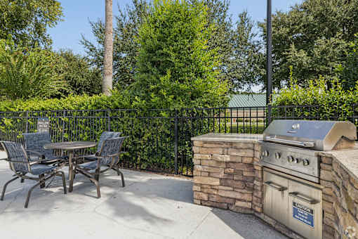 A patio with a grill and chairs.