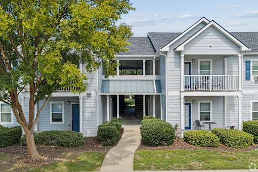A two-story house with a blue door and a balcony.