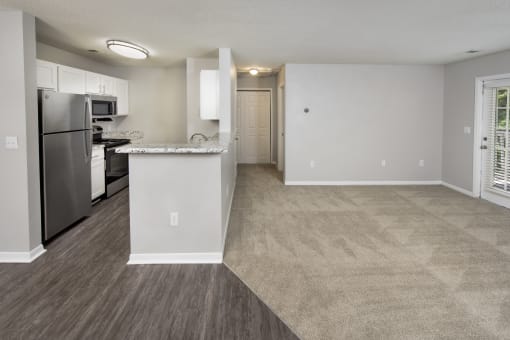 an empty kitchen and living room with a stainless steel refrigerator