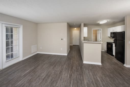 an empty living room and kitchen with a large window