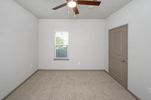 A room with a ceiling fan and a door.