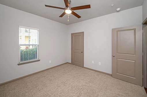 A room with a ceiling fan and two doors.