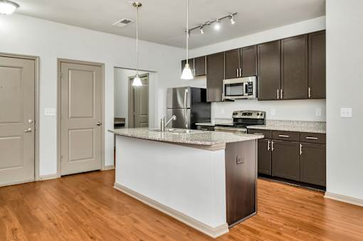 A kitchen with a white island and wooden floors.