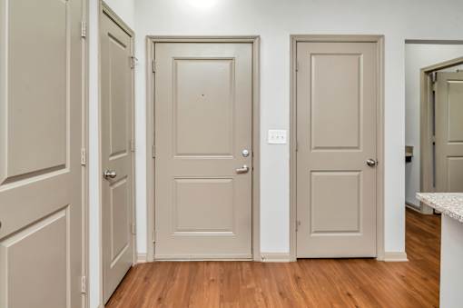 A hallway with three doors and a white counter.
