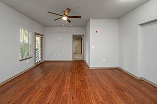 A room with a ceiling fan and wooden floors.