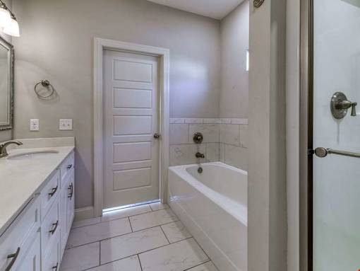 A white bathroom with a tub, sink, and shower.