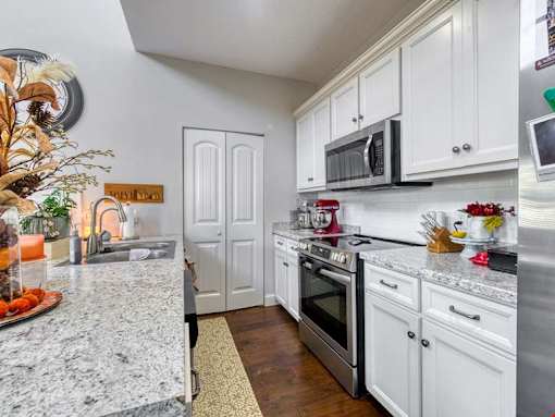 A kitchen with white cabinets and a marble countertop.