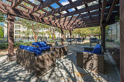 A wooden pergola with blue cushions and a concrete floor.