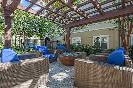 A patio with brown wicker furniture and a wooden pergola.