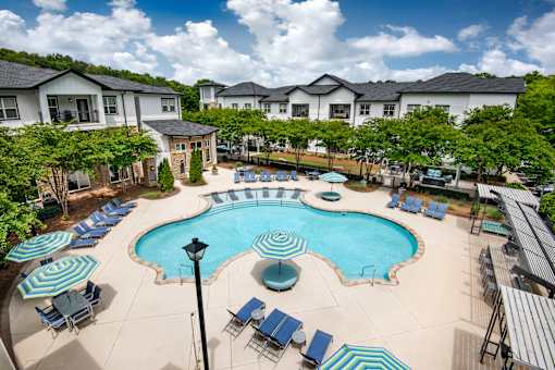 A large swimming pool surrounded by lounge chairs and umbrellas.