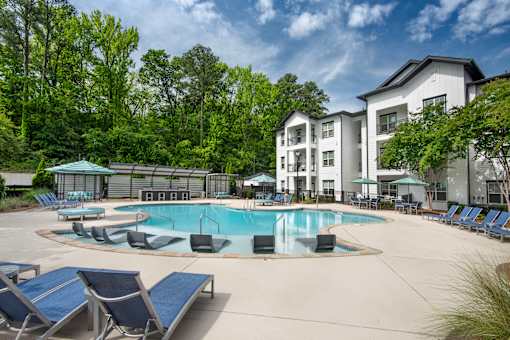 A large swimming pool surrounded by lounge chairs and trees.