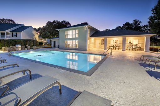a swimming pool with chairs around it in front of a house