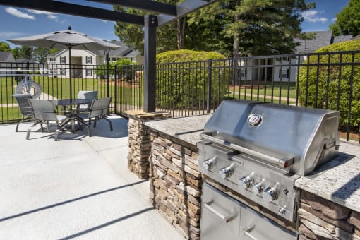 a patio with a grill and a table with chairs