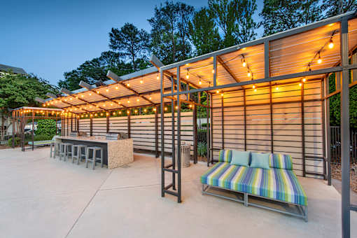A patio with a striped couch and a table with a bench.