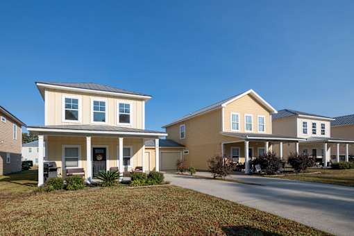Two houses with front porches and a clear blue sky above.