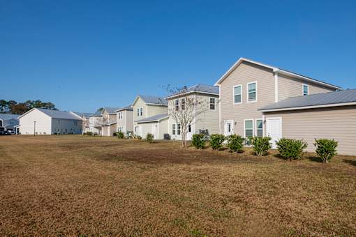 A row of houses with a brown grass field in front.