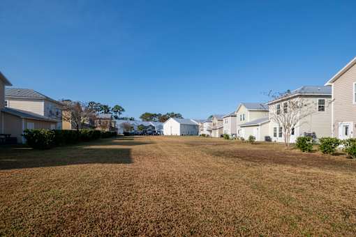 A grassy field with houses in the background.