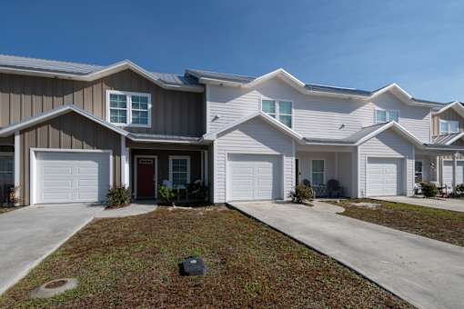 A row of houses with garages and front yards.