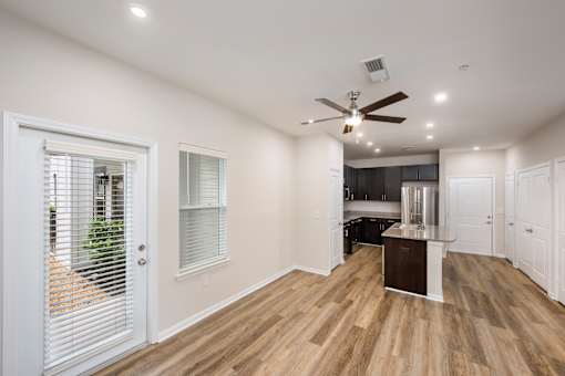 A spacious room with wooden flooring and a ceiling fan.