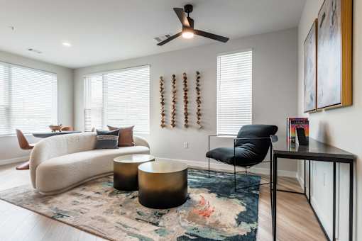 A living room with a black chair and a rug.